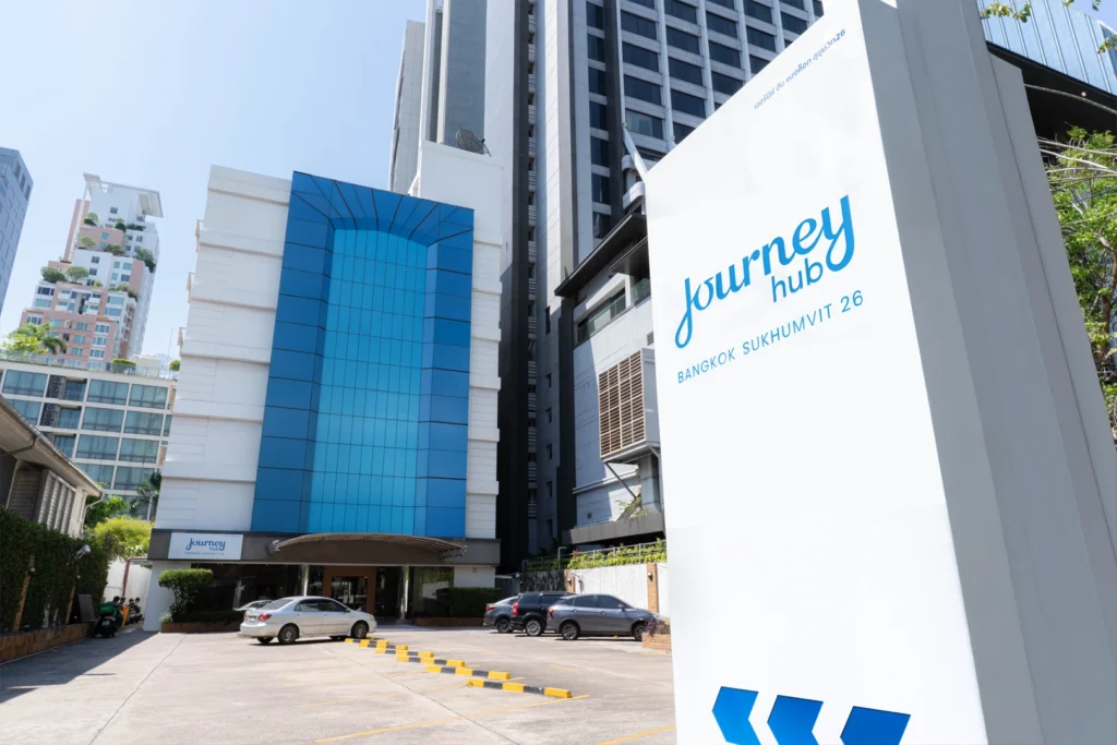 Outdoor parking area in front of Journeyhub Bangkok Sukhumvit 26, a hotel near BTS Phrom Phong, with private vehicle access and clear hotel signage.